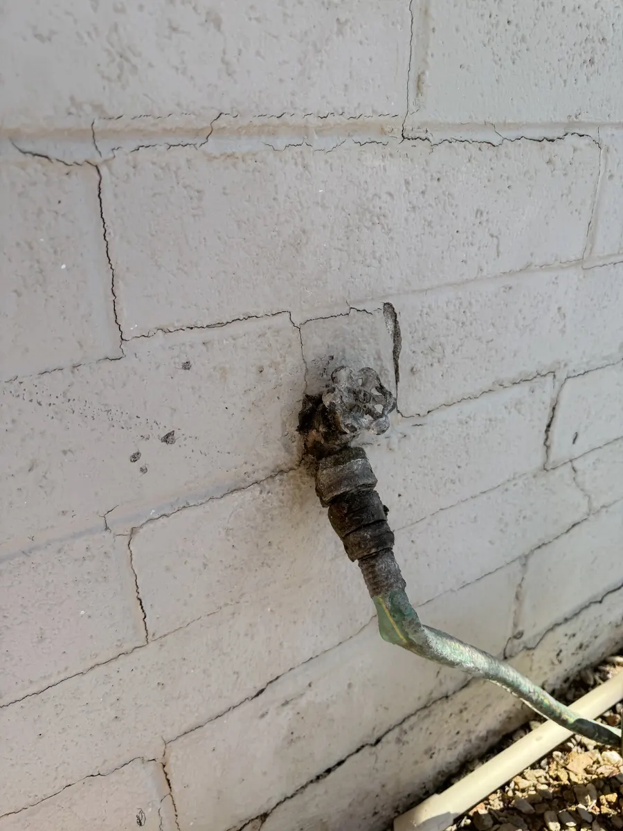 Corroded, leaking hose bib on a block wall at a Tempe home