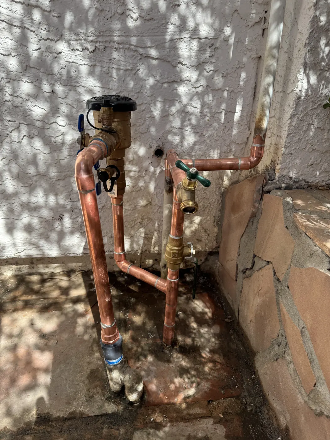 New copper water line with a pressure regulator and hose bib at a block wall in Chandler