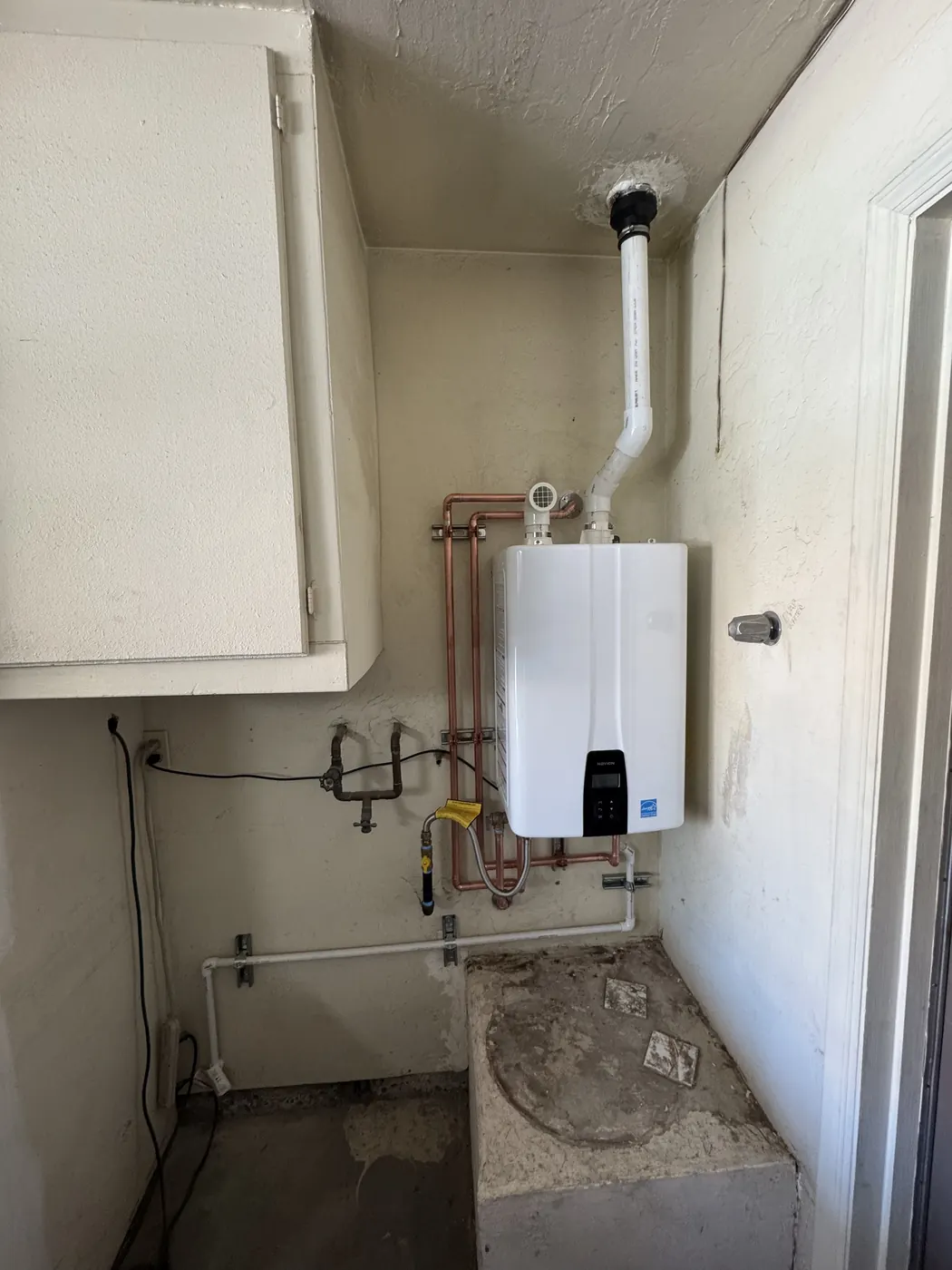 Tankless water heater in a Tempe laundry room with gas and copper water connections