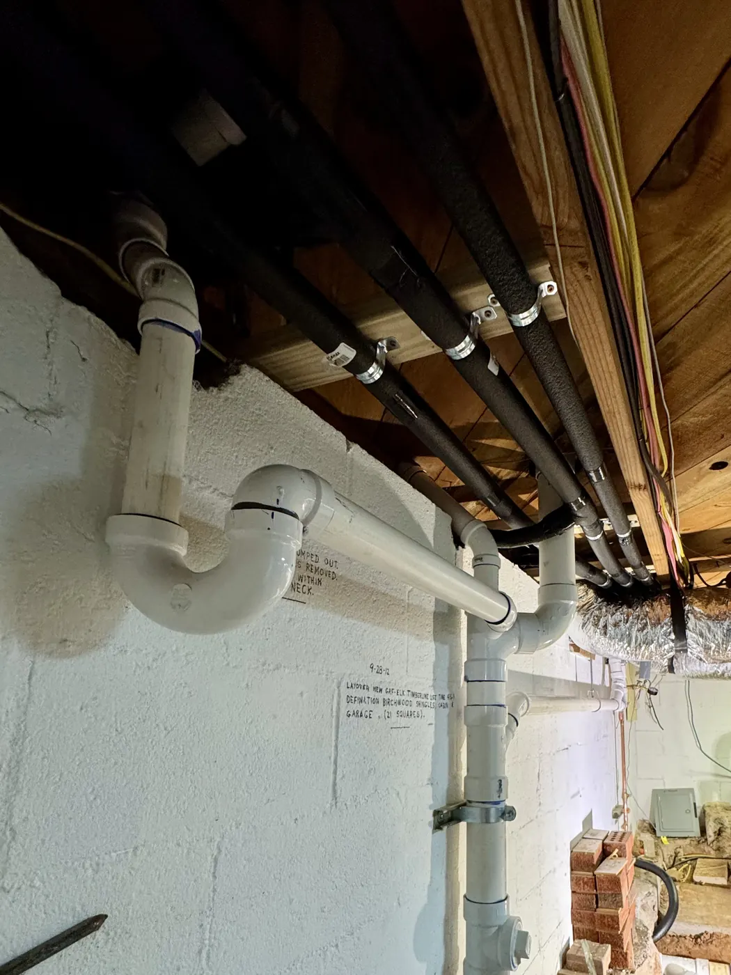 New white PVC drain and vent lines installed under a floor