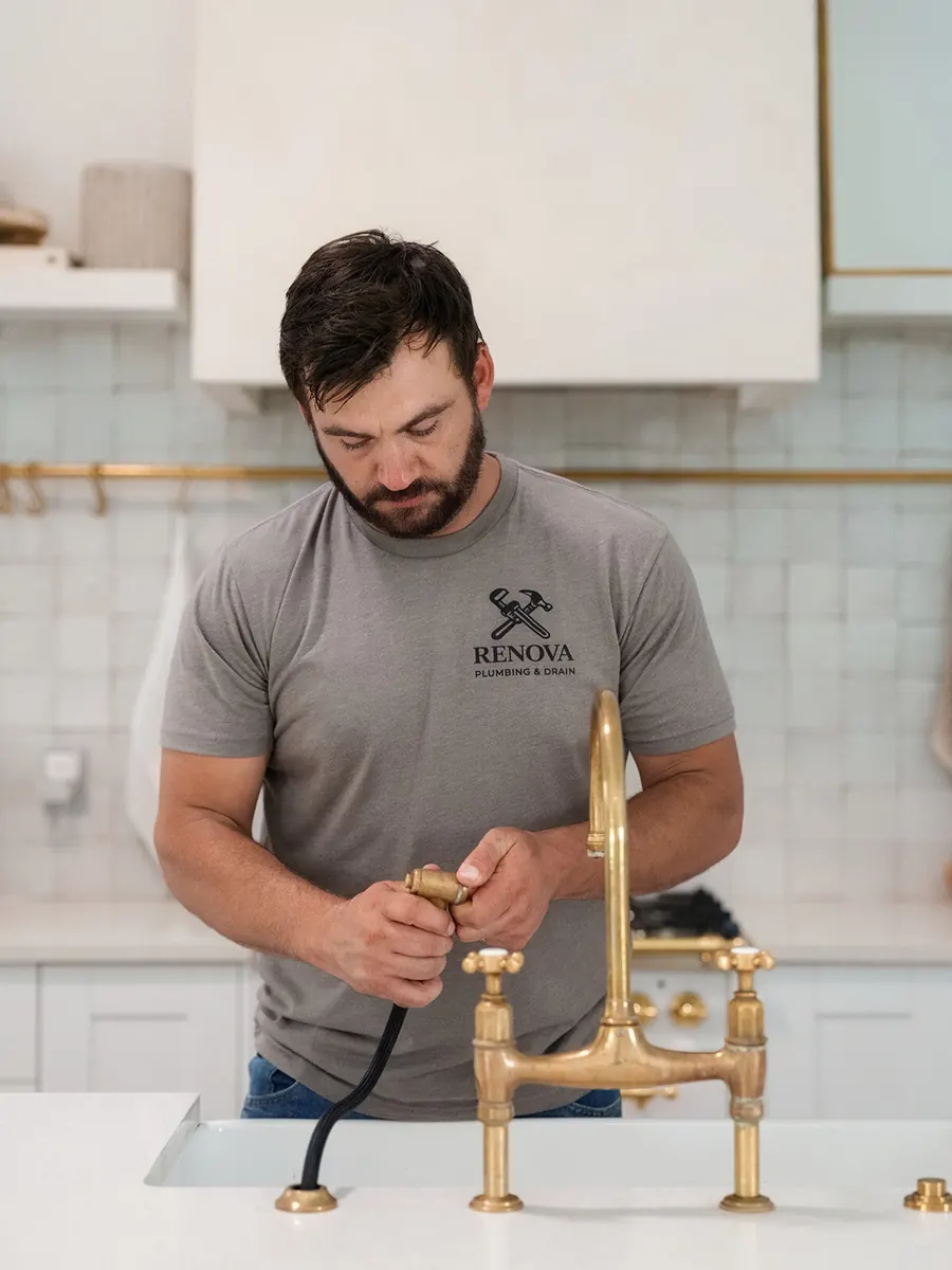 Luke Williams, owner of Renova Plumbing & Drain, installing a brass kitchen faucet